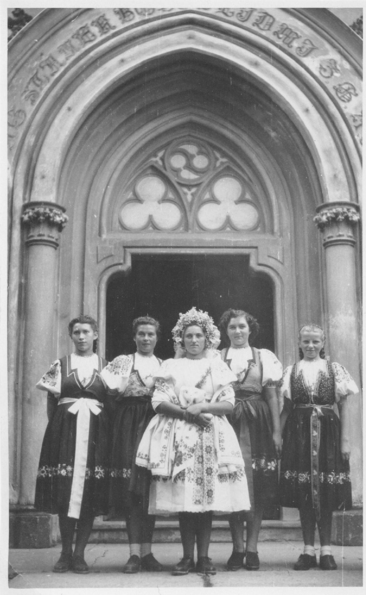 Krojované dievčatá (v strede svadobný) pred evanjelickým kostolom v  Púchove v r. 1904