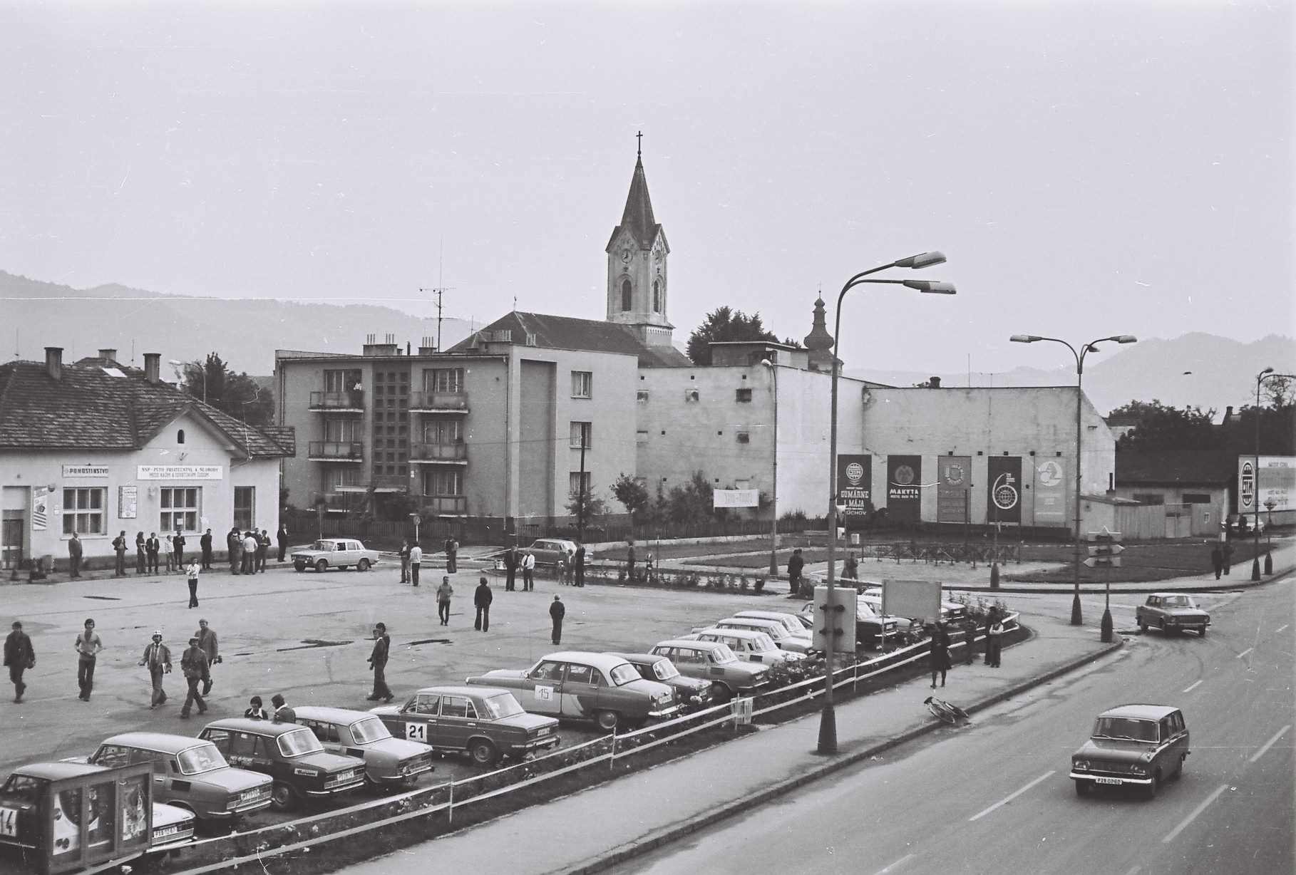 Dnešná Hollého ulica s parkoviskom, budovou starej pošty prerobenej na pohostinstvo (dnes Púchovčan) a pódium na mieste dnešnej pizzerie (Valdagno) v prvej polovici 70. rokov 20. storočia