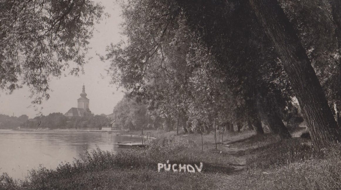 Pohľad na nábrežie Váhu pri Púchove z tzv. Horného parku v roku 1930. Pohľadnica od pána S. Mikulu zachytila pôvodné neregulované koryto Váhu, rovnako neprestavaný katol. kostol a malý prístav