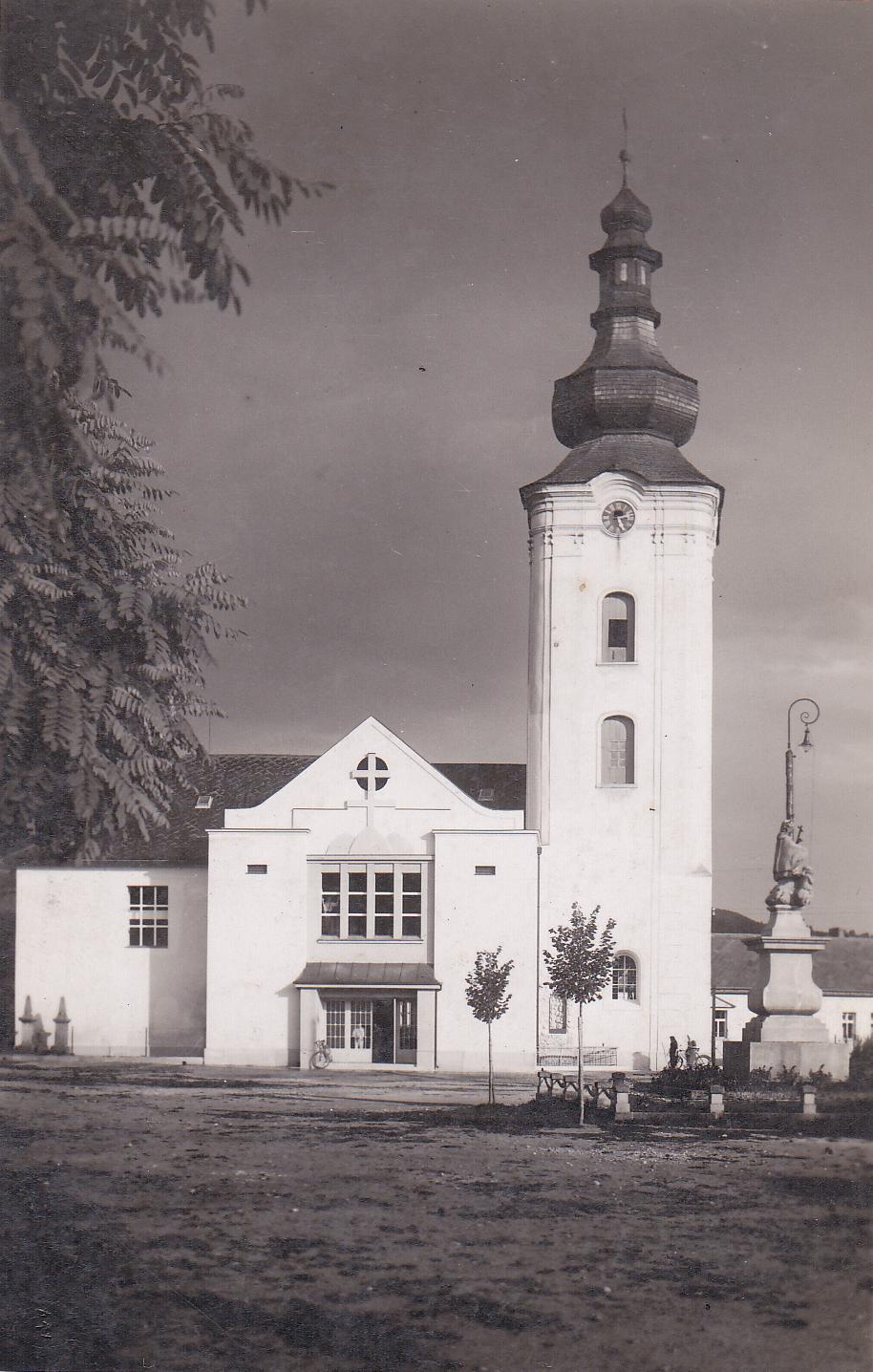 Námestie slobody v r. 1947 v Púchove: nedávno zasadené lipy a ohradenie okolo sochy sv. Jána Nepomuckého, dobové lampy,  čierne ciferníky na vežových hodinách