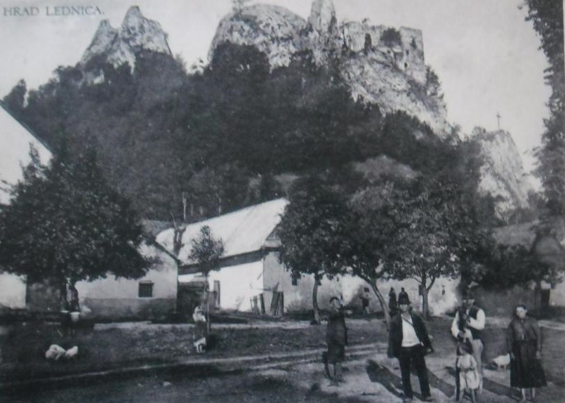 Hrad Lednica na dobovej pohľadnici zachytený z rovnomennej obce spolu s obyvateľmi na začiatku 20. storočia